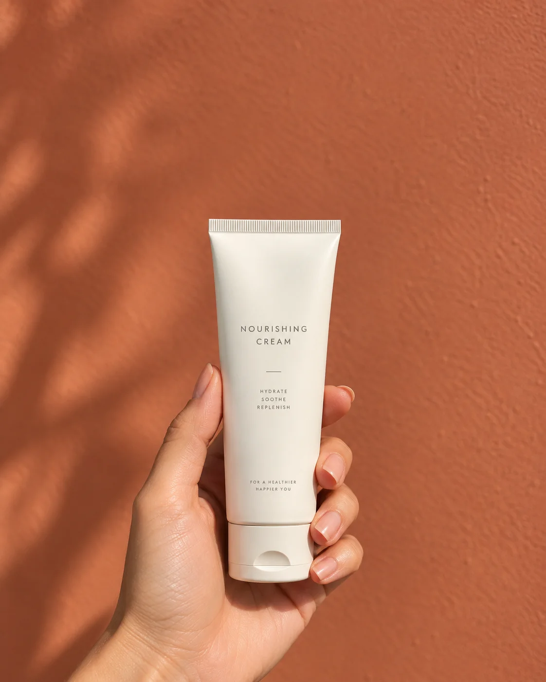 Cosmetic tube held in a woman's hand against a terracotta background, social ad format